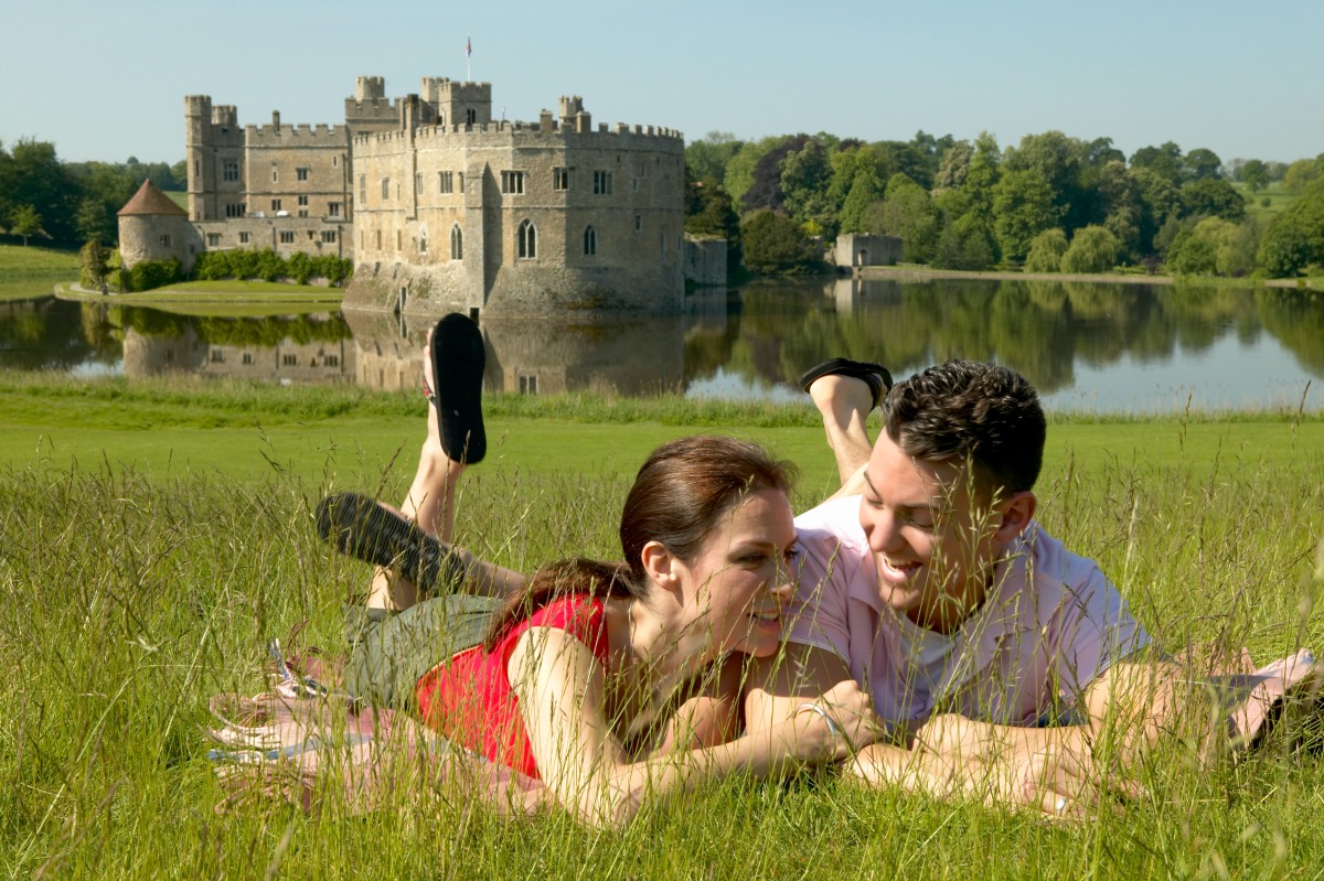 Couple enjoying a day out at Leeds Castle, relaxing in the grounds surrounding the 12th Century fortified manor house on the River Len in the heart of Kent, Leeds Castle, Maidstone, Kent, England. Additional Credit: Kent Tourism Alliance