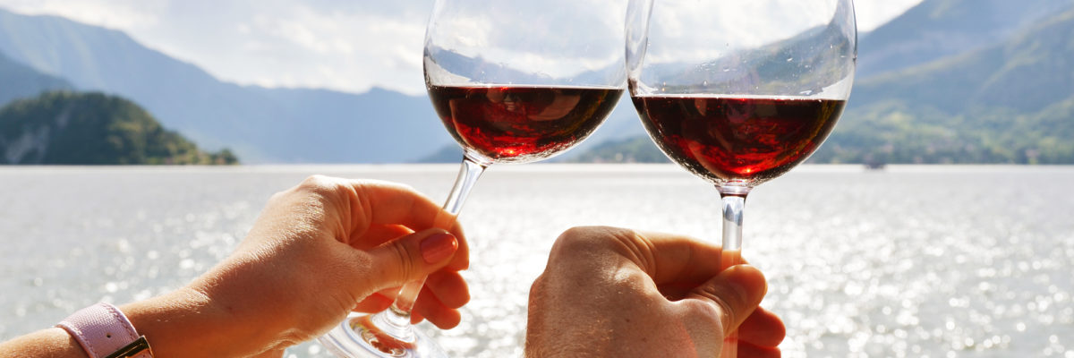 Wineglasses in the hands against lake Como, Italy / Image: happyalex, Deposit Photos