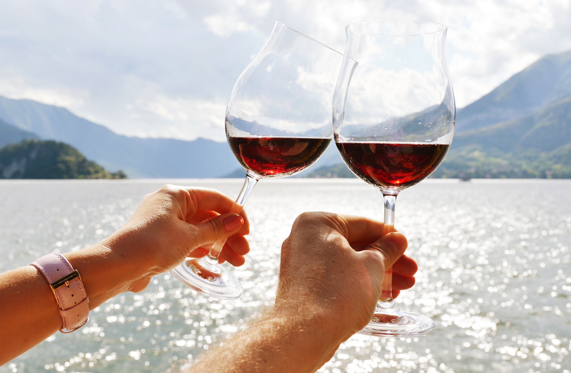 Wineglasses in the hands against lake Como, Italy / Image: happyalex, Deposit Photos